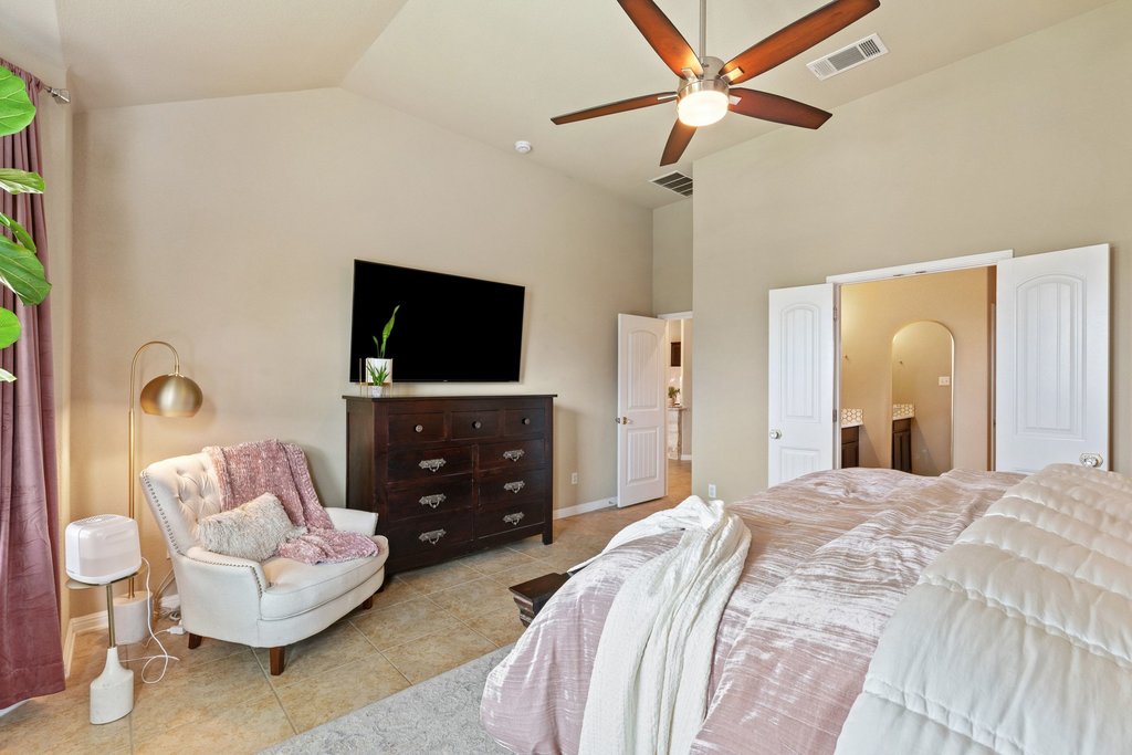 13808 Field Stream Lane Manor, TX 78653 - Photo 22 of 39 Bedroom with lofted ceiling, ceiling fan, ensuite bath, light tile patterned floors, and arched walkways