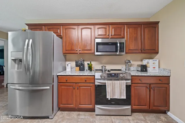 a kitchen with stainless steel appliances granite countertop a refrigerator stove and microwave