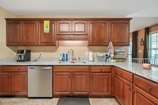 a kitchen with granite countertop wooden cabinets a sink and dishwasher