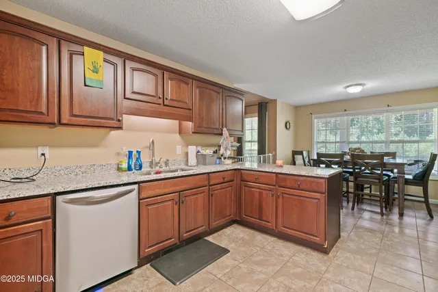 a kitchen with stainless steel appliances granite countertop wooden cabinets a sink a stove a dining table and chairs
