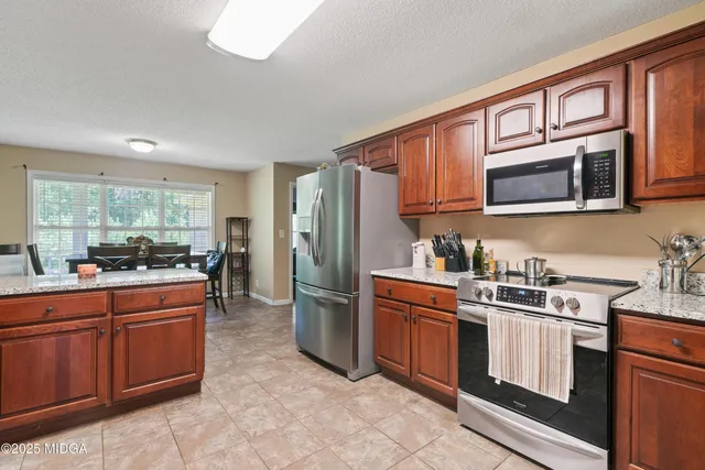 a kitchen with stainless steel appliances granite countertop a stove top oven a sink dishwasher a refrigerator and cabinets with wooden floor