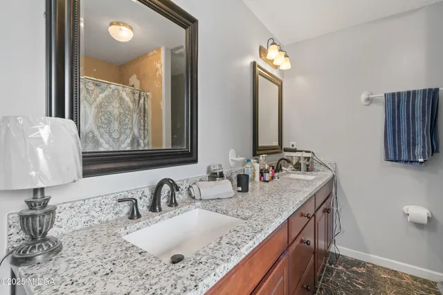 a bathroom with a granite countertop sink and a mirror