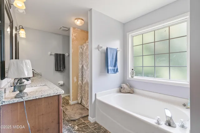 a bathroom with a granite countertop sink and a bathtub