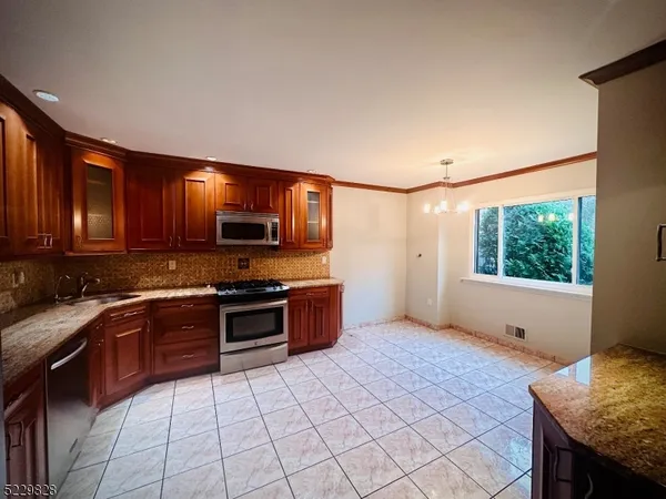 a kitchen with stainless steel appliances granite countertop a stove top oven a sink a counter space and cabinets