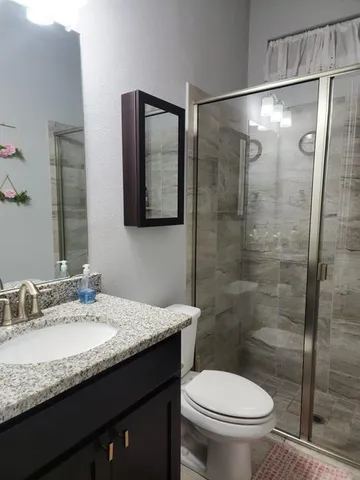 a bathroom with a granite countertop sink toilet and shower