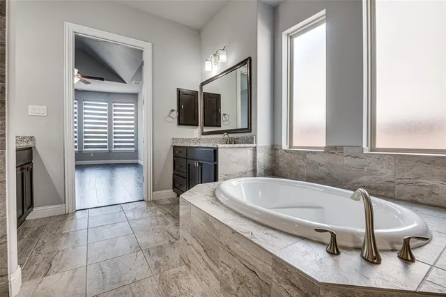 a spacious bathroom with a bathtub and a flat screen tv