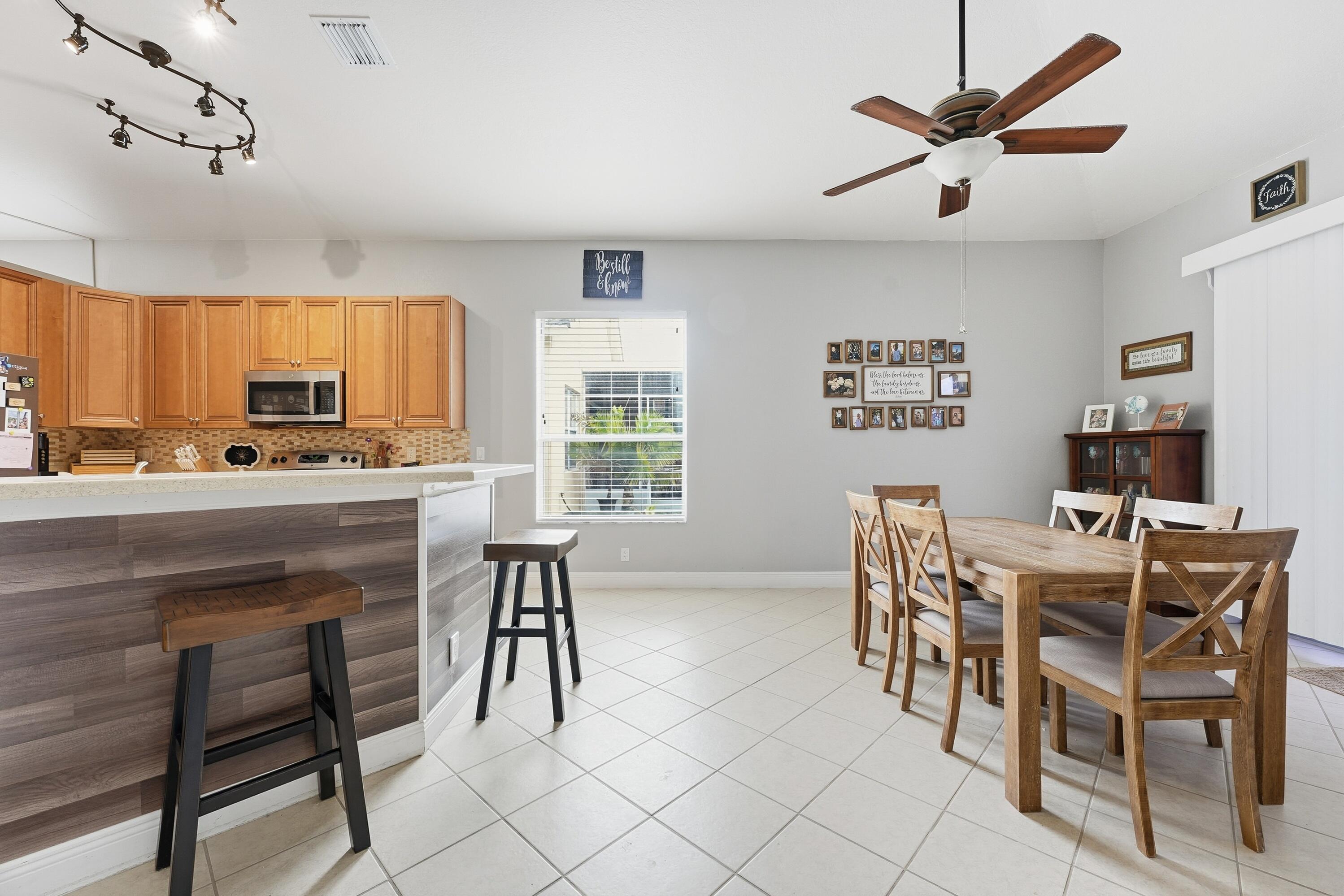 6117 Spring Lake Terrace Fort Pierce, FL 34951 - Photo 12 of 38 a kitchen with stainless steel appliances kitchen island granite countertop a dining table chairs and a refrigerator