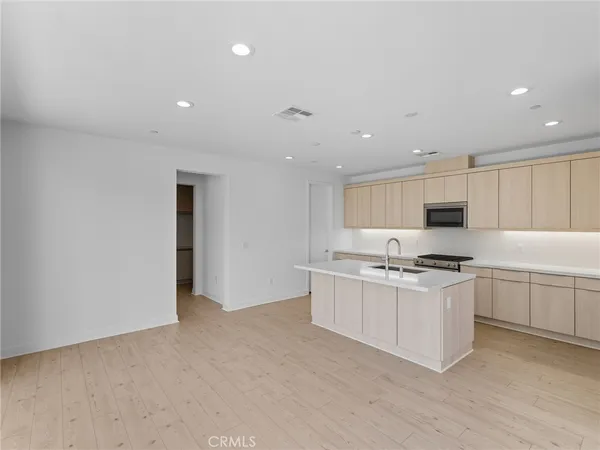 a kitchen with stainless steel appliances a stove top oven a sink a refrigerator and white cabinets