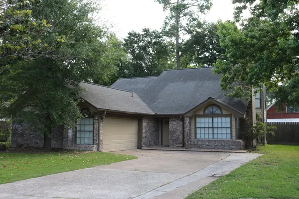 a front view of a house with a garden and trees