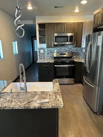 a kitchen with kitchen island granite countertop a stove refrigerator and microwave