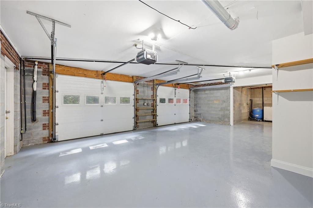 8861 Boylston Road Colfax, NC 27235 - Photo 35 of 50 Oversized attached basement garage with three bays, epoxy-coated floors, dedicated workshop space, and abundant storage. Utility closet houses the tankless water heater (2022).