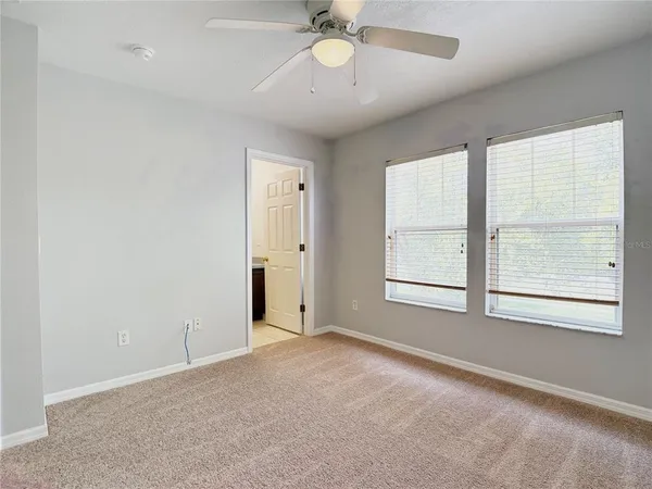 an empty room with chandelier fan and windows