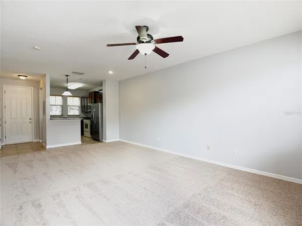 an empty room with a kitchen and a ceiling fan