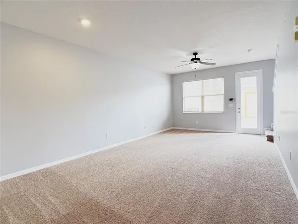 an empty room with a window and ceiling fan