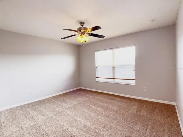 an empty room with windows and chandelier fan