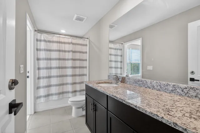 a bathroom with a granite countertop sink a toilet and shower