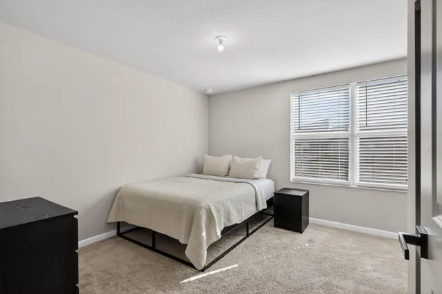 a bedroom with a bed lamp and a window