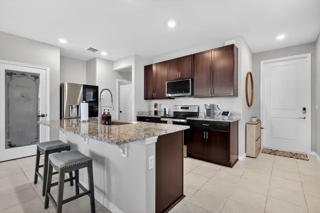 a large kitchen with kitchen island granite countertop a stove top oven a sink dishwasher a refrigerator and a oven with wooden cabinets