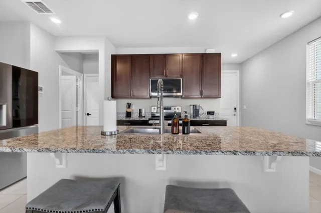 a kitchen with kitchen island granite countertop a sink stove and refrigerator