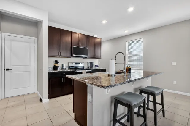 a kitchen with stainless steel appliances granite countertop a stove a sink a microwave a refrigerator and cabinets