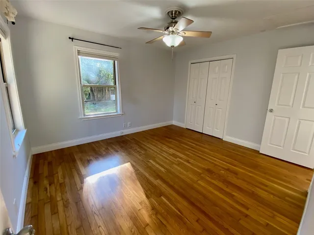 a view of empty room with wooden floor and fan