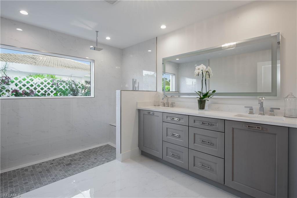 512 Whispering Pine Lane Naples, FL 34103 - Photo 11 of 24 a bathroom with a double vanity sink and a mirror