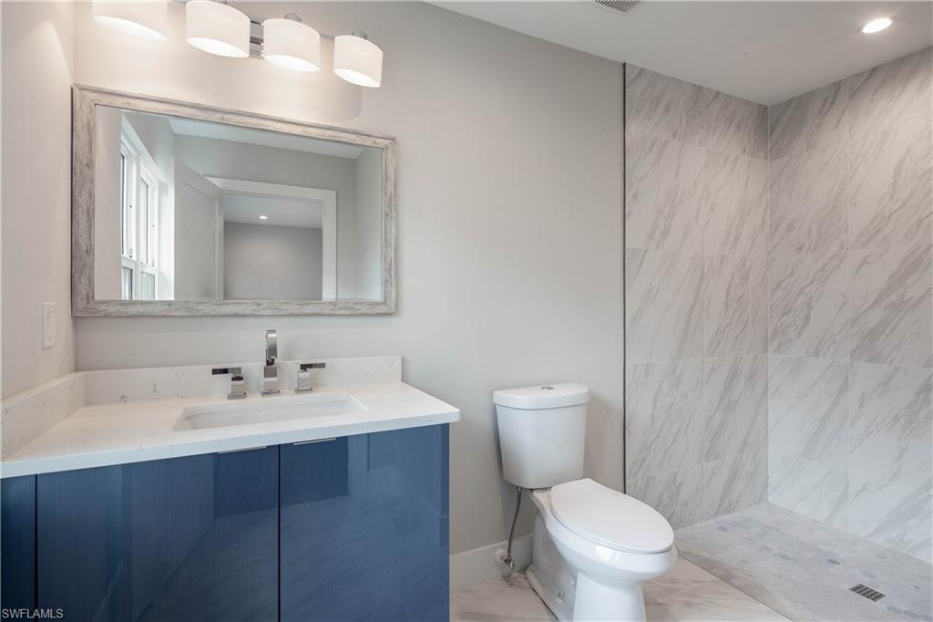 512 Whispering Pine Lane Naples, FL 34103 - Photo 17 of 24 a bathroom with a toilet a sink and mirror