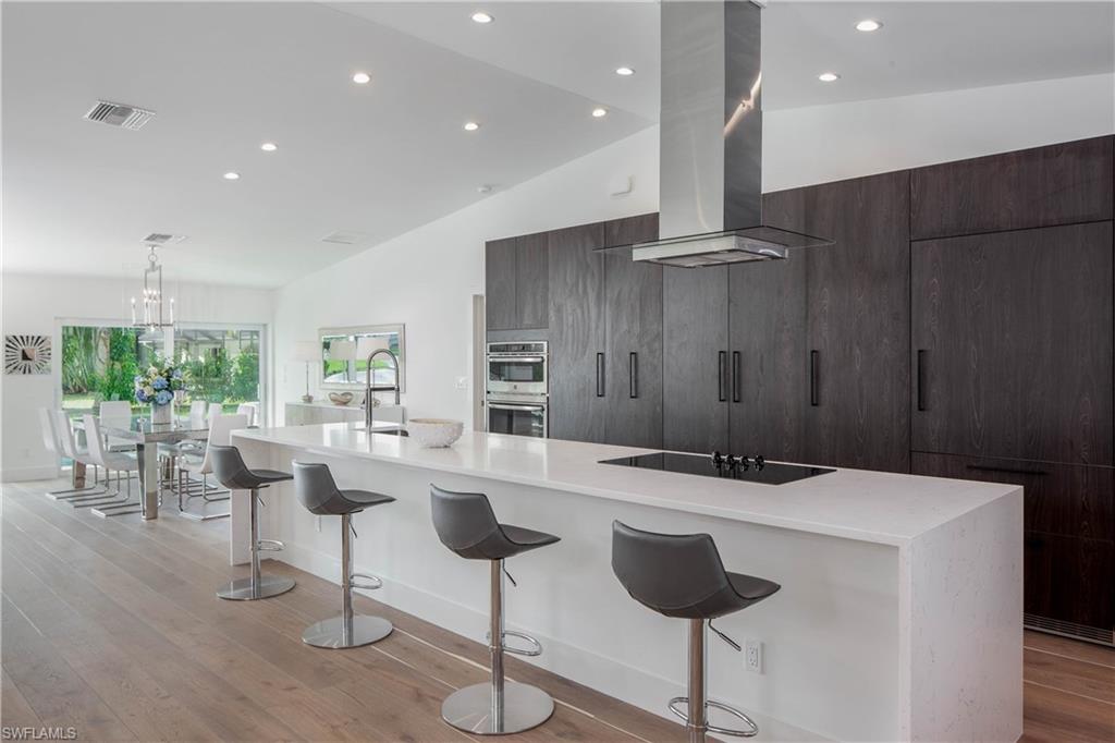 512 Whispering Pine Lane Naples, FL 34103 - Photo 5 of 24 a kitchen with a dining table chairs sink and stove