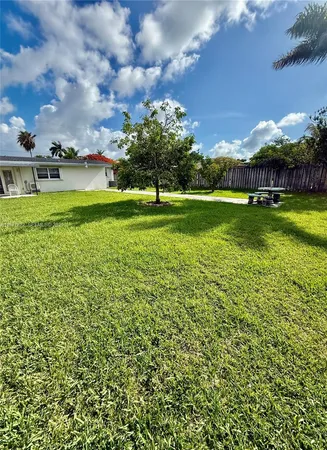 a view of a big house with a big yard and large trees