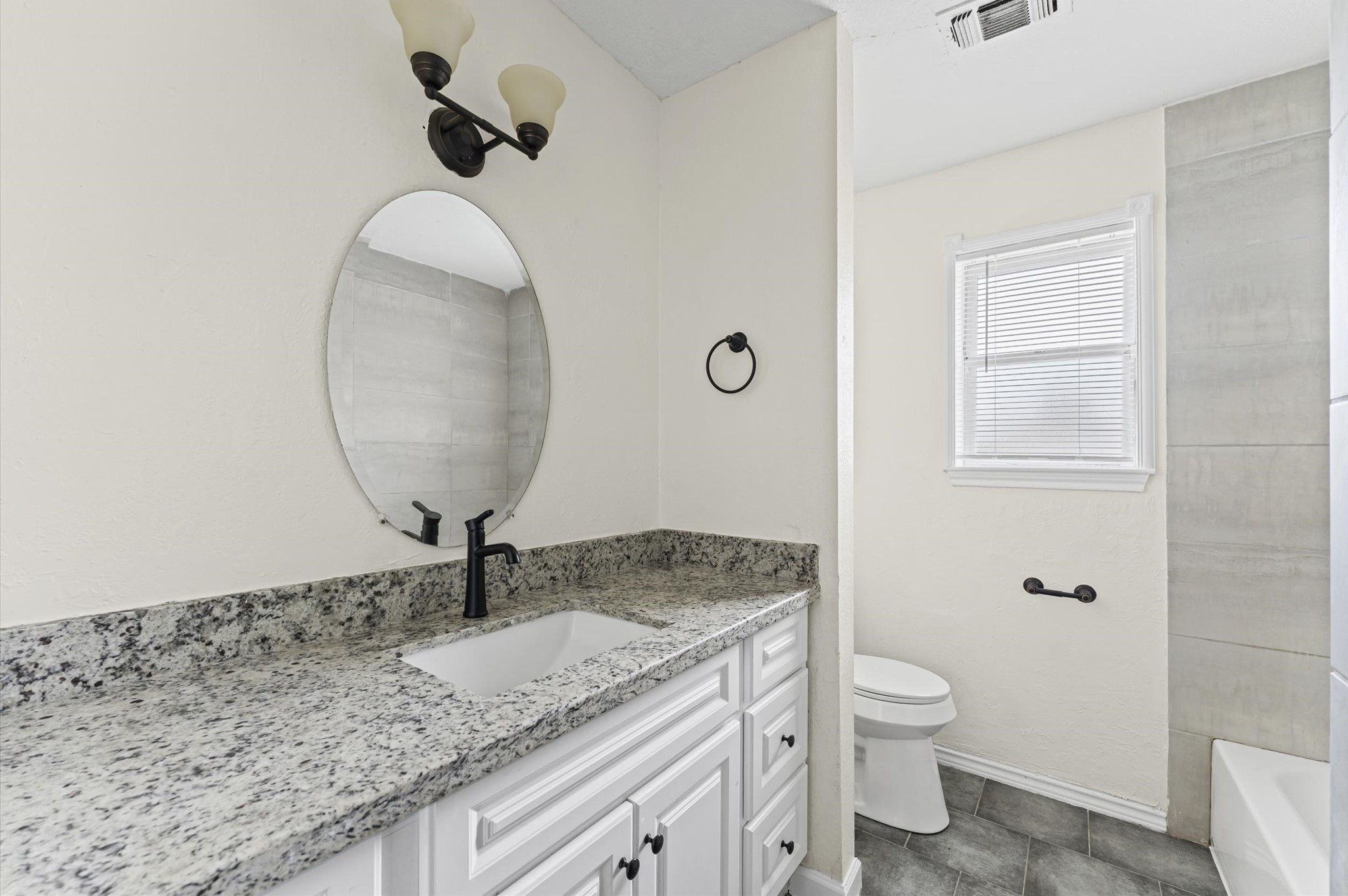 2709 Adams Street Alvin, TX 77511 - Photo 21 of 32 a bathroom with a granite countertop sink a toilet and a mirror