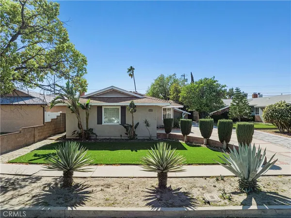 a front view of a house with a yard and potted plants