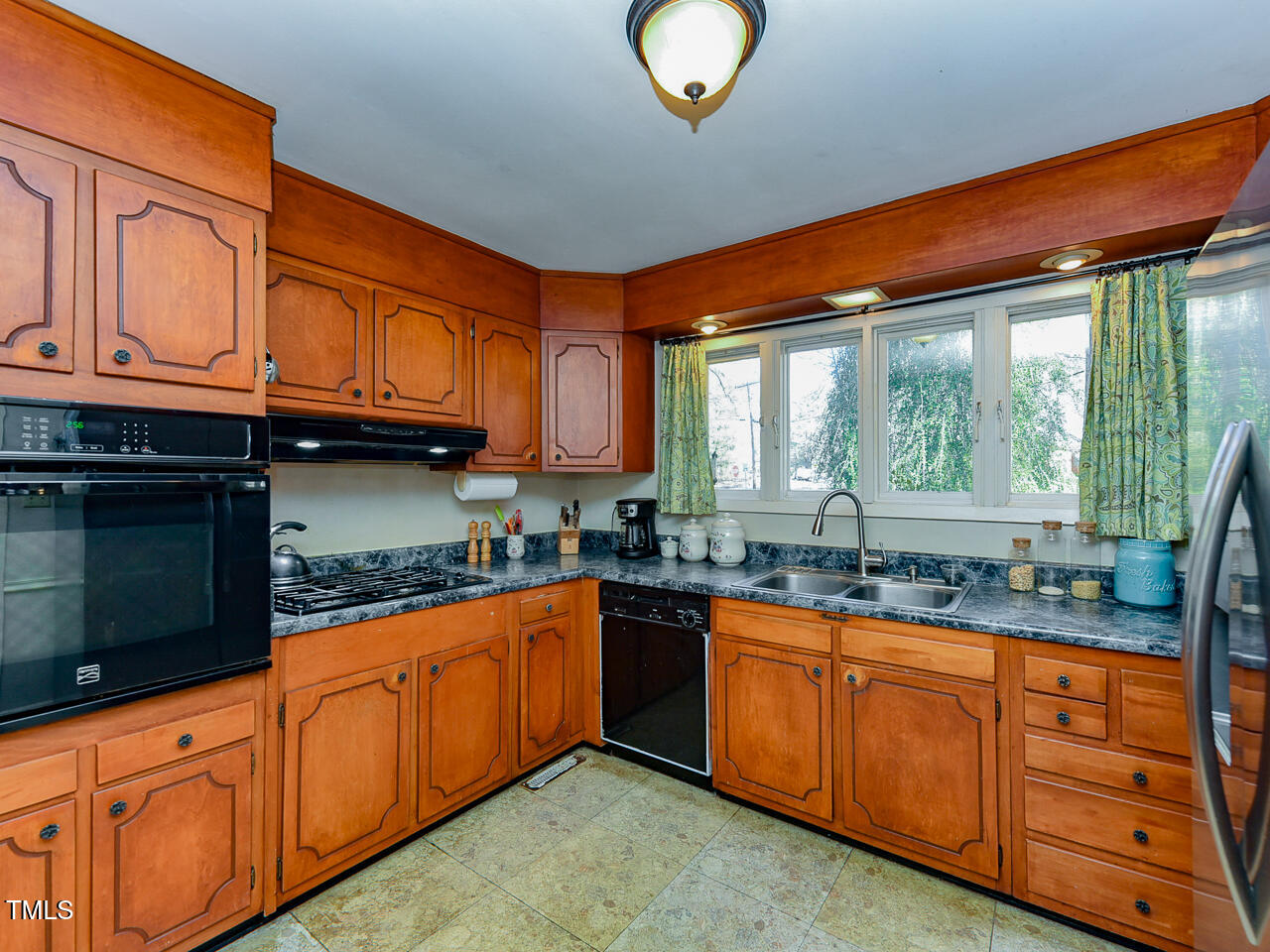 5200 Newhall Road Durham, NC 27713 - Photo 21 of 35 a kitchen with granite countertop wooden cabinets a sink a window and stainless steel appliances