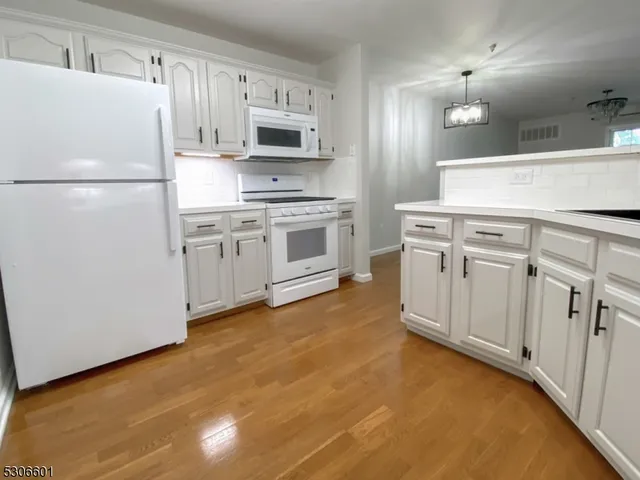 a kitchen with kitchen island a white cabinets and refrigerator