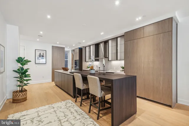 a kitchen with stainless steel appliances granite countertop a dining table chairs and white cabinets