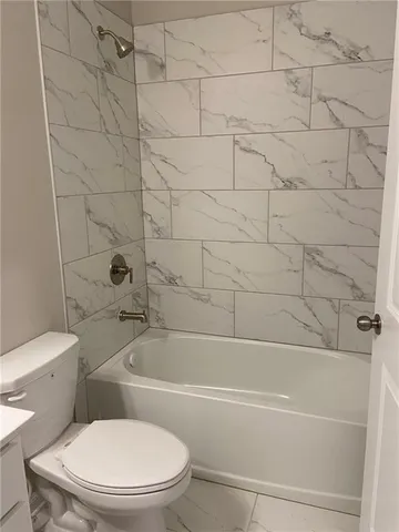 a white toilet and tub sitting next to a bathroom sink