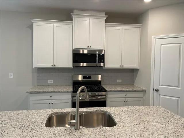 a kitchen with granite countertop a sink a stove and cabinets