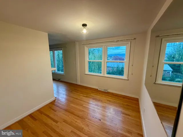 a view of an empty room with glass door and wooden floor