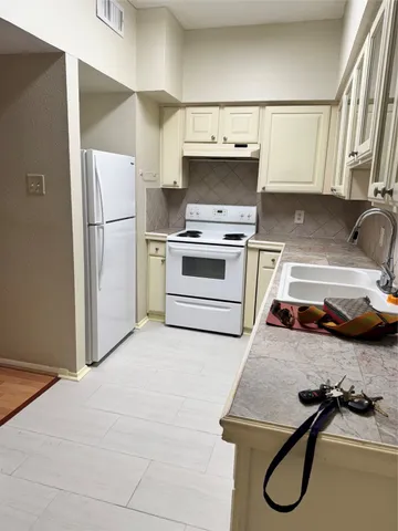 a kitchen with a refrigerator sink and white cabinets