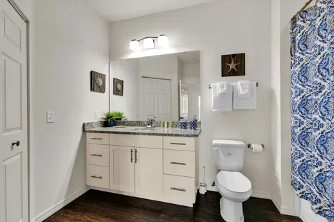 a bathroom with a granite countertop toilet sink and mirror
