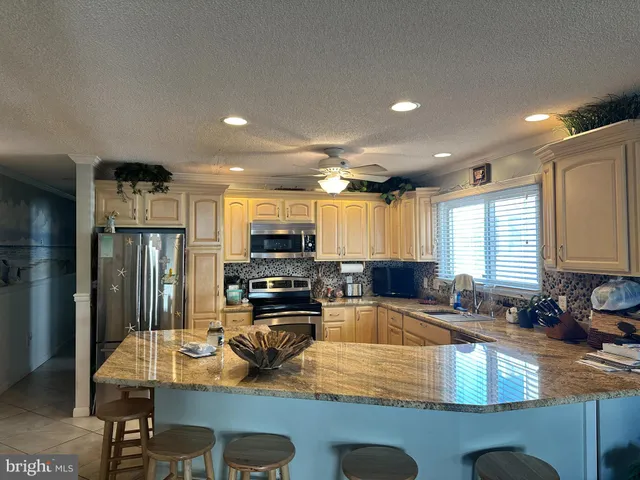 a kitchen with kitchen island granite countertop a stove sink refrigerator dining table and chairs
