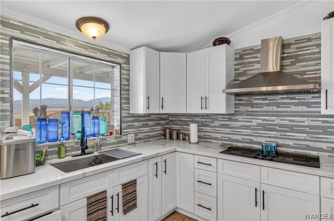 784 Pegasus Ranch Road Bullhead City, AZ 86429 - Photo 15 of 100 Modern kitchen featuring white shaker cabinetry with black hardware, white stone-finish countertops, and a gray-toned linear mosaic tile backsplash