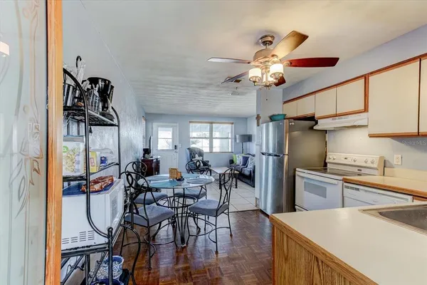 a kitchen with stainless steel appliances granite countertop a refrigerator a sink dishwasher a stove and a dining table with wooden floor