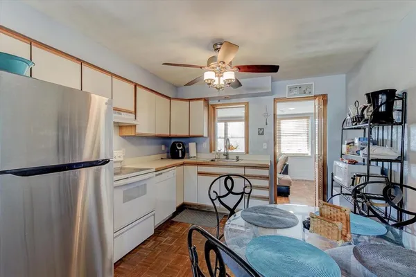 a kitchen with stainless steel appliances granite countertop a refrigerator a sink dishwasher a dining table and chairs with wooden floor