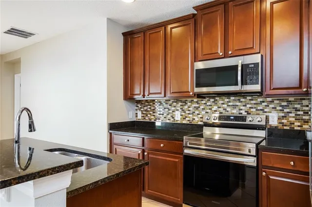 a kitchen with granite countertop a stove sink and microwave