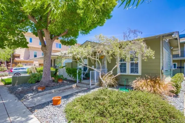 a backyard of a house with table and chairs plants and large tree