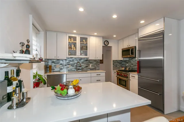 a kitchen with stainless steel appliances kitchen island granite countertop a sink and refrigerator