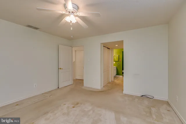 a view of an empty room and chandelier fan