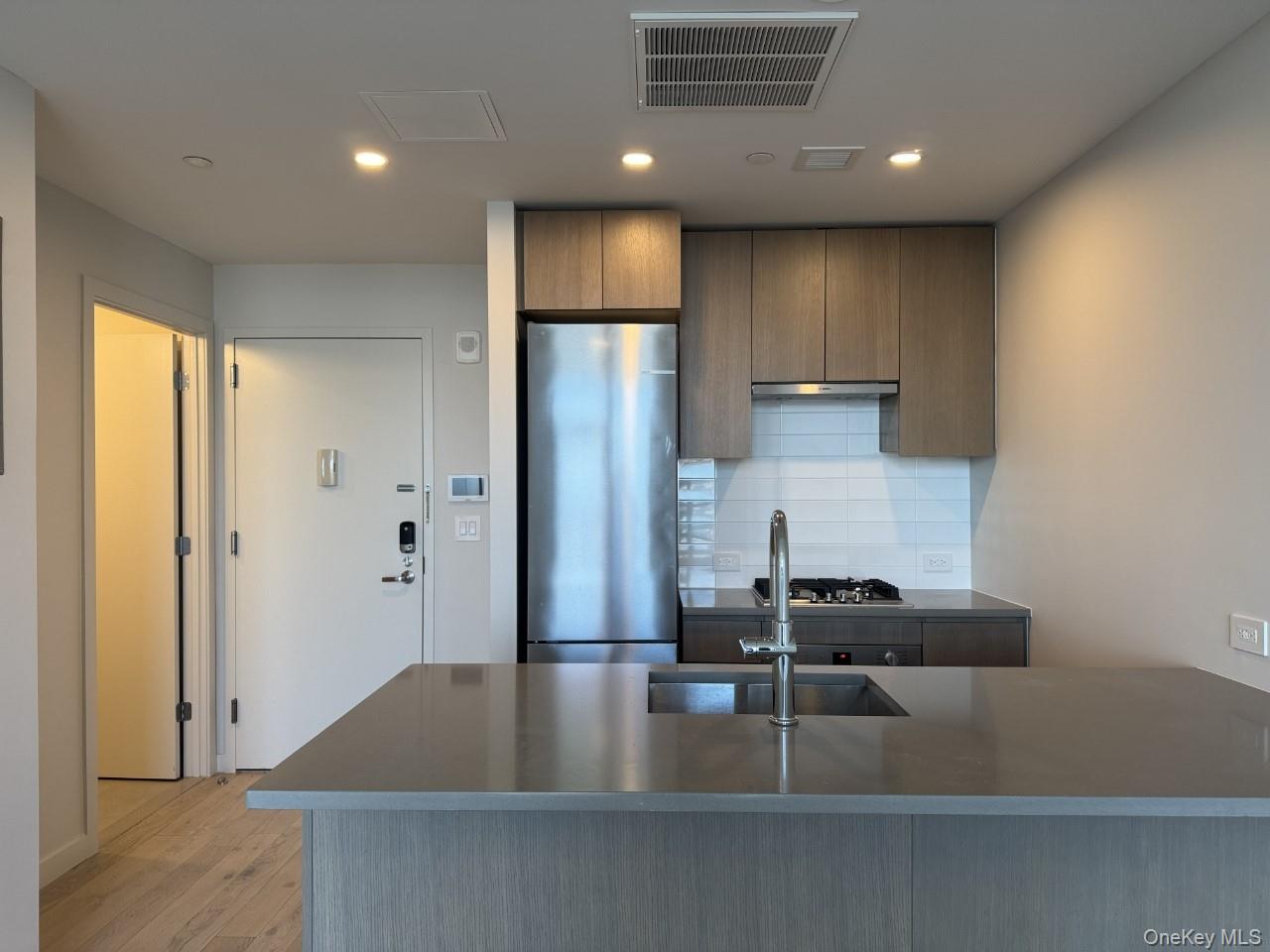 131-02 40th Road, Unit 9O Queens, NY 11354 - Photo 14 of 24 a kitchen with kitchen island a counter top space cabinets and stainless steel appliances