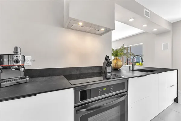 a kitchen with a sink and a stove with wooden floor