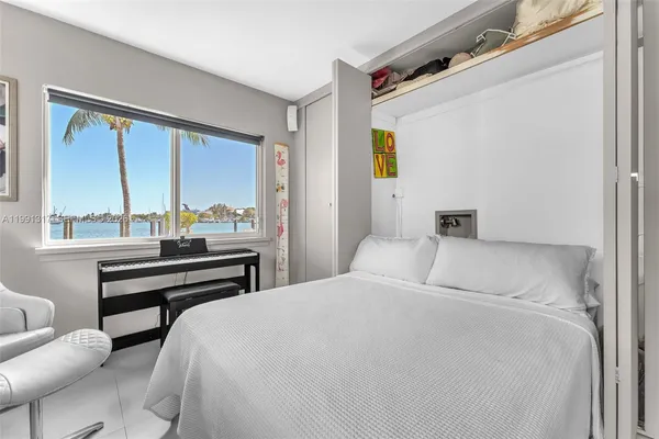 a bedroom with a bed wooden floor and a large window